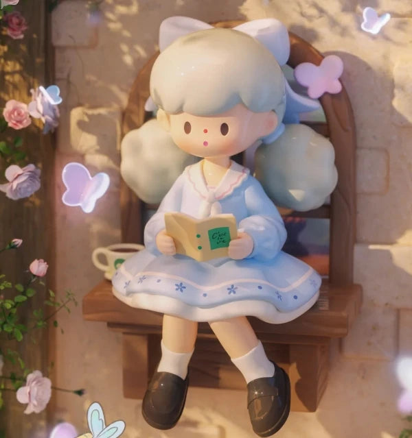 Plush toy of a character with cat ears sitting on a bench, holding a book.