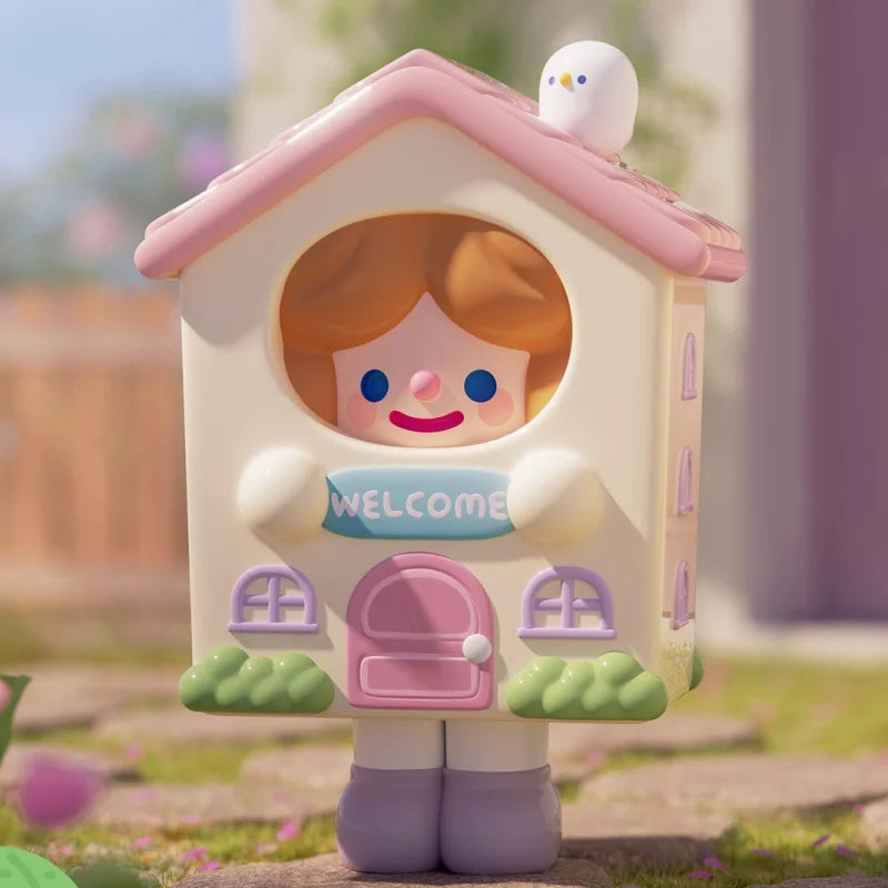 Toy figure of a house with a face, holding a 'Welcome' sign, in a garden setting.