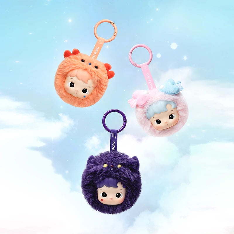 Three plush keychains with cartoon faces on a light blue background