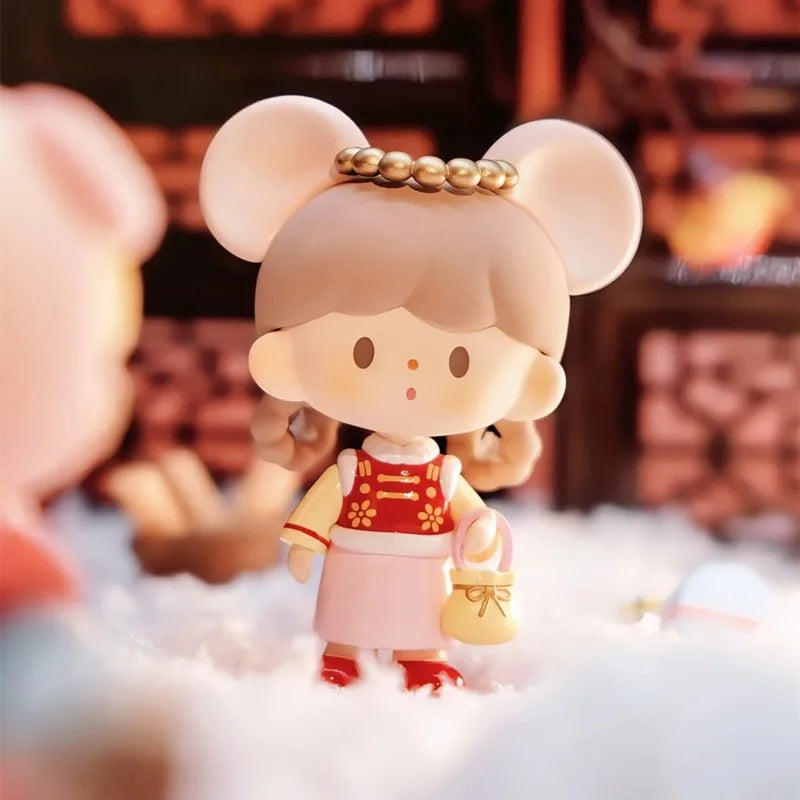 Small figurine of a character with large ears, wearing a red outfit with gold accents, on a soft white surface.