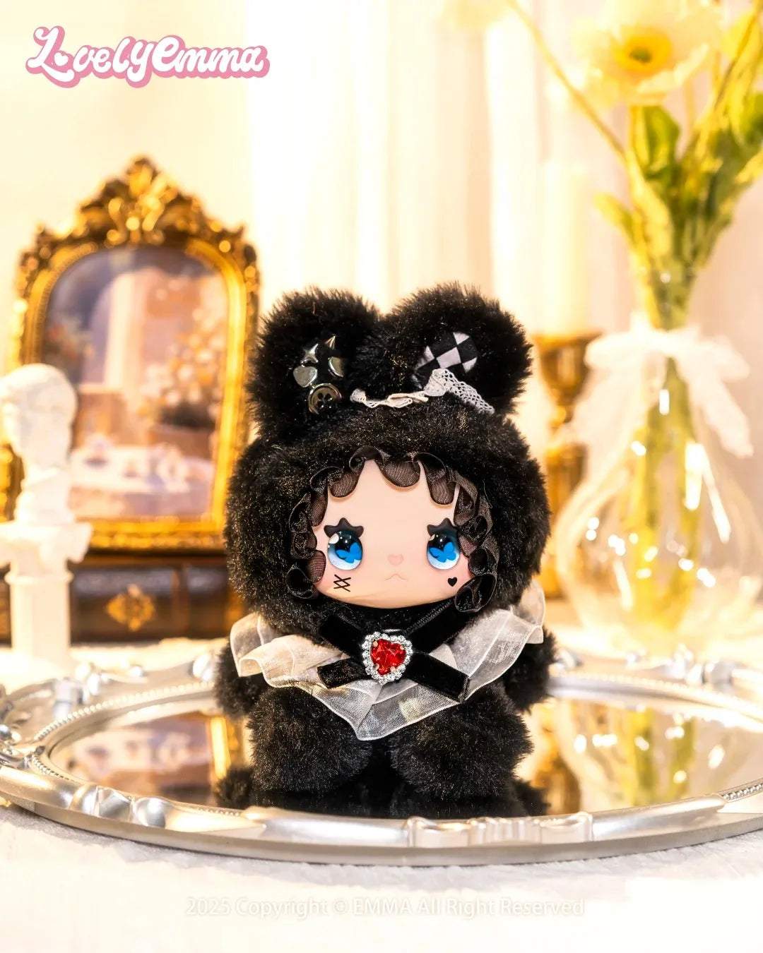 Small plush toy with black hair and blue eyes on a reflective surface, with 'Lovely Emma' branding.