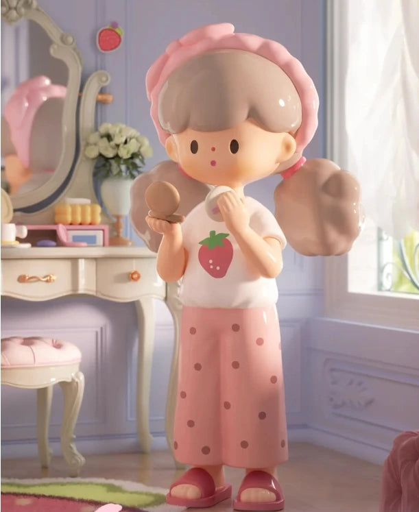 Toy figure of a girl with a strawberry shirt and pink skirt in a room setting.