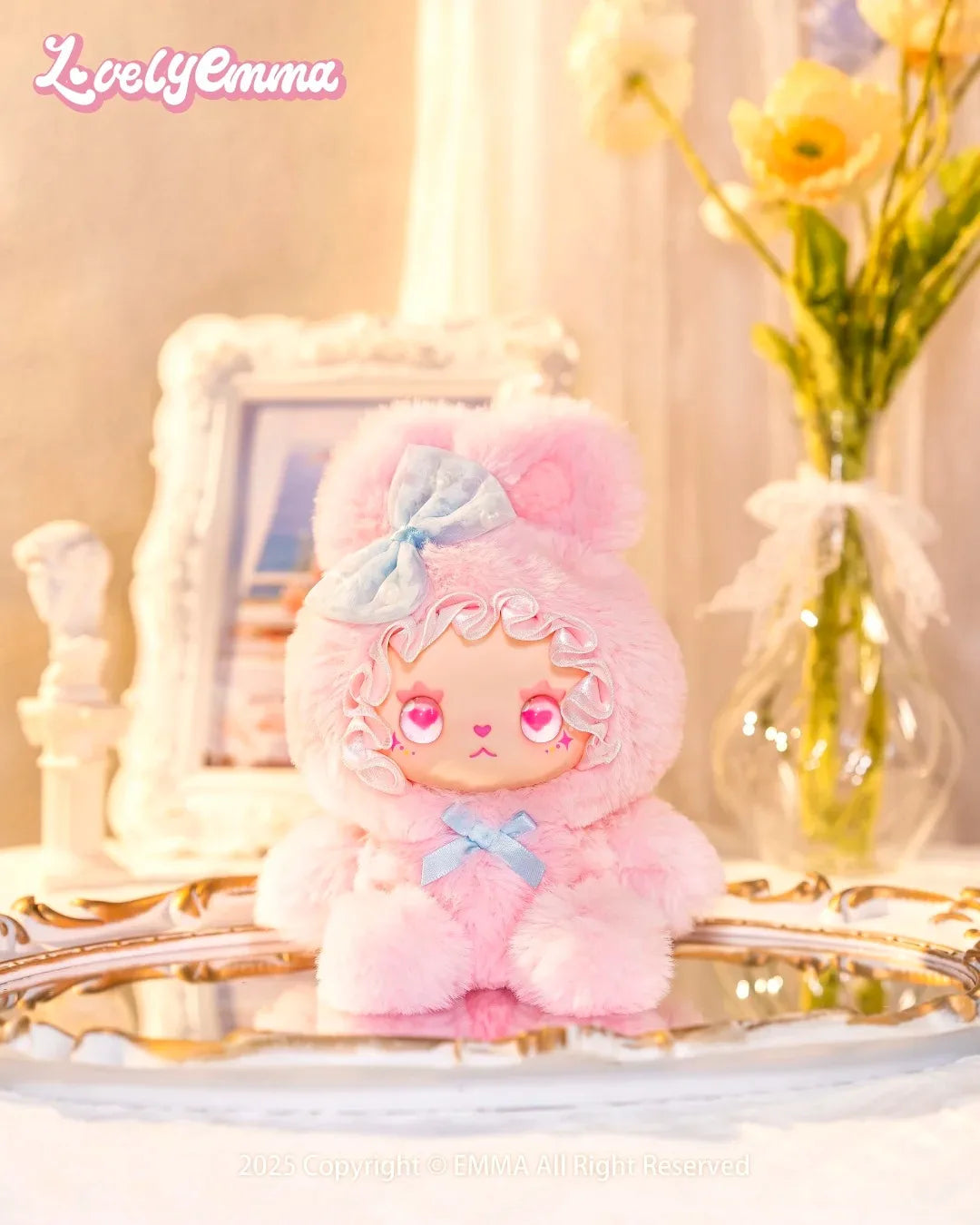 Pink plush toy with a bow on a decorative surface with 'LovelyEmma' branding.