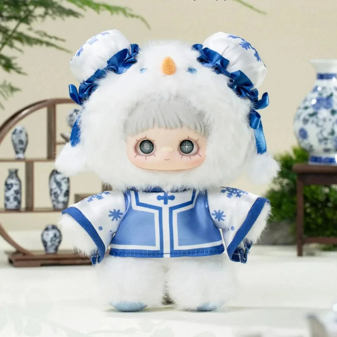 Toy figure in a blue and white outfit with a fur-lined hood, standing indoors.