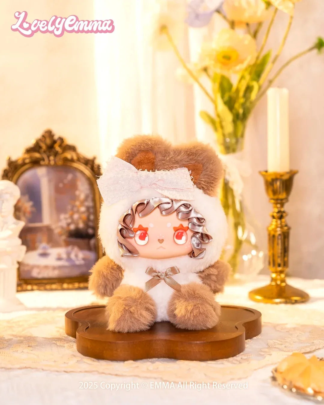 Stuffed animal toy with a fluffy white hood and brown body on a decorative stand, with 'Lovely Emma' branding.