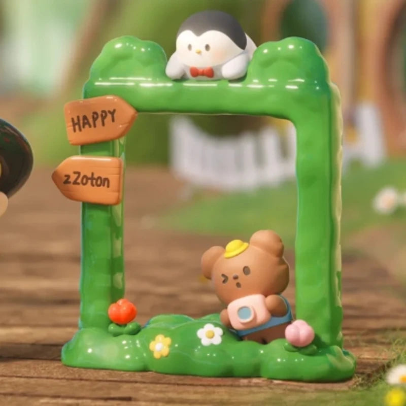 Toy figurines of a penguin and bear inside a green arch with 'Happy ZZoton' sign on a wooden surface.