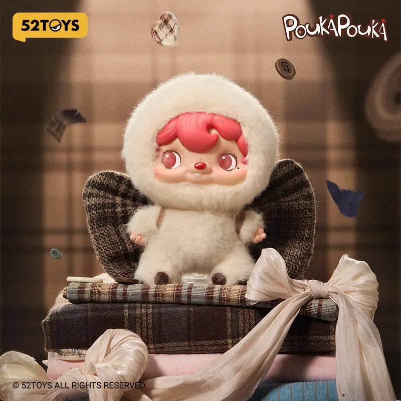 Stylized toy figure with red hair and white fur sitting on a suitcase, surrounded by small objects.