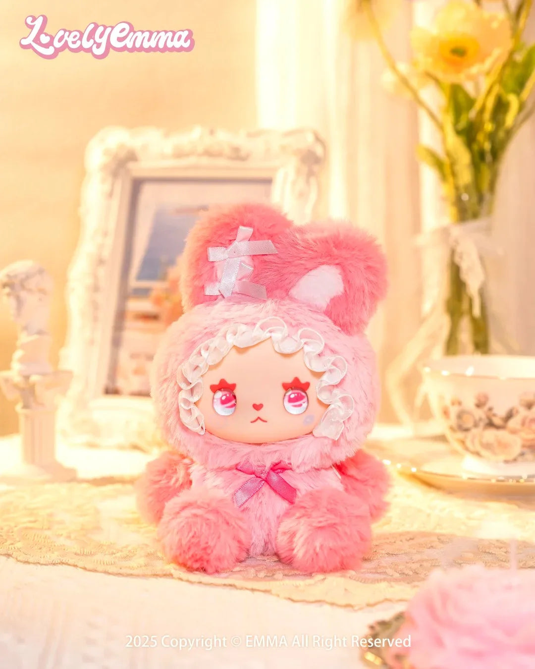 Pink plush toy with bunny ears on a decorative surface with 'Lovely Emma' branding.