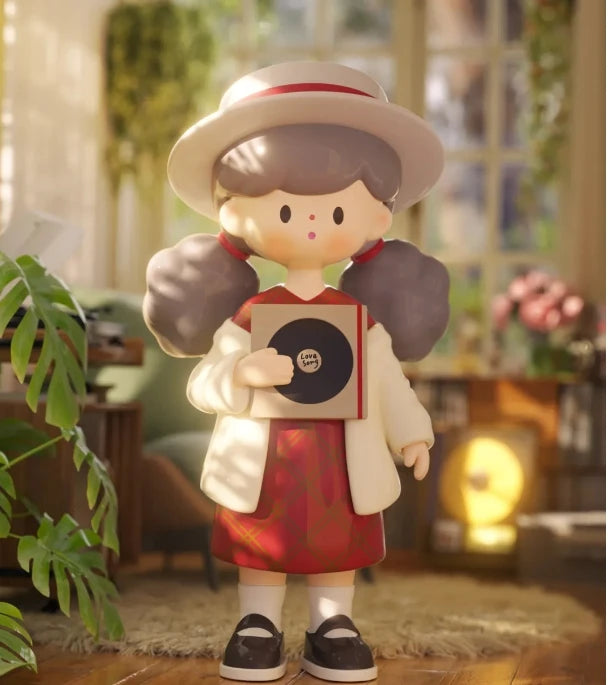 Decorative figurine of a girl holding a record in a home setting with plants and furniture.
