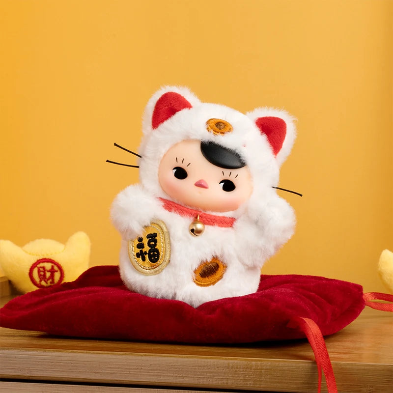 Plush toy resembling a cat with a traditional outfit on a red pillow against a yellow background