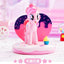 Pink pony figurine on a heart-shaped platform with a donut background