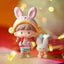 Toy figure of a girl with bunny ears and a small rabbit in front of colorful lights