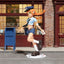 Figurine of a character in a school uniform standing next to a blue mailbox on a street.
