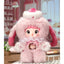 Pink plush toy with bunny ears and a pacifier in a decorative setting
