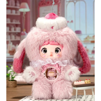 Pink plush toy with bunny ears and a pacifier in a decorative setting
