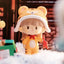 Toy figure of a character with a tiger hat and outfit, holding a red object, on a soft white surface.