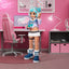 Gaming setup with a character figurine in a room with pink walls and gaming furniture.