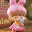 Toy figure of a girl with bunny ears and pink outfit on a wooden surface
