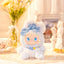 Plush toy with blue accents and a bow on a decorative surface with flowers and a mirror in the background.