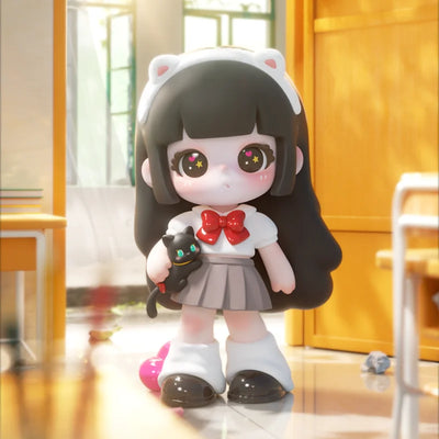 Plush toy with black hair, white outfit, and cat ears holding a small black cat plush toy in a room.