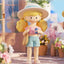 Toy figure of a girl with a hat and sunglasses in a garden setting