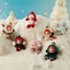 Collection of small dolls in winter-themed outfits on a snowy background with snowmen.
