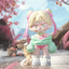Toy figure with pink hair and green outfit in a cherry blossom setting