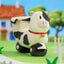 Plush cow toy with a bell on a farm-themed background