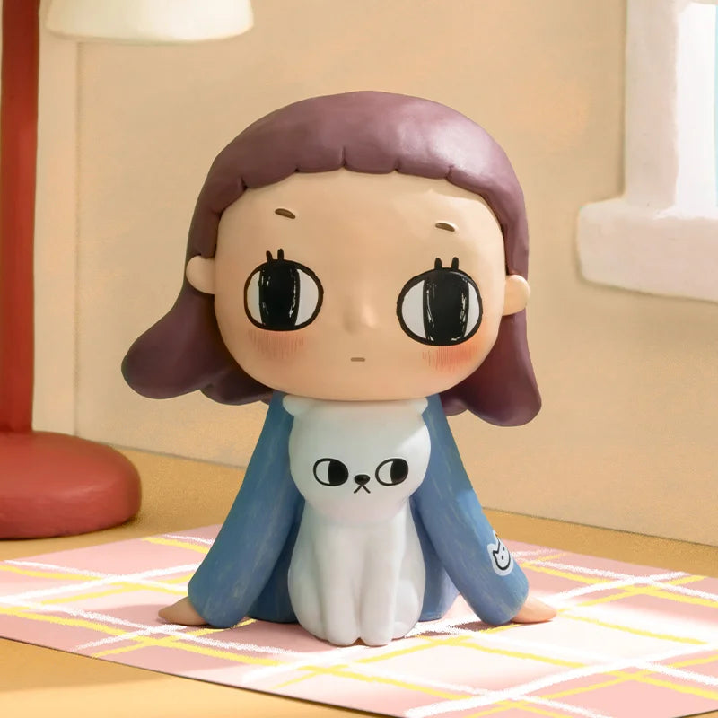 Cartoon figurine of a girl with brown hair and a blue outfit on a checkered floor.