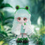 Frog-themed figurine with a green headband and white outfit against a blurred green background