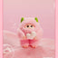 Cute plush toy with pink fur and green ears on a pink background, holding a heart-shaped object.