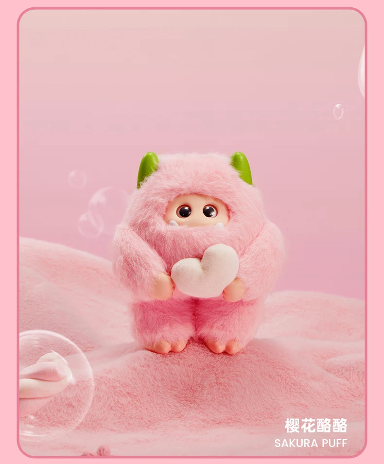 Cute plush toy with pink fur and green ears on a pink background, holding a heart-shaped object.
