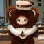Plush toy with brown fur, white accents, and a crown-like headpiece in a blurred indoor setting.