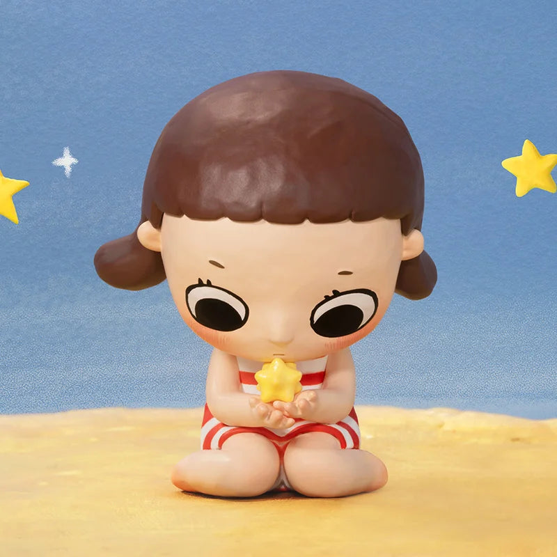 Toy figure of a child holding a star against a blue sky with stars