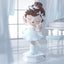 Decorative figurine of a ballerina in a white dress with brown hair, standing on a light surface.