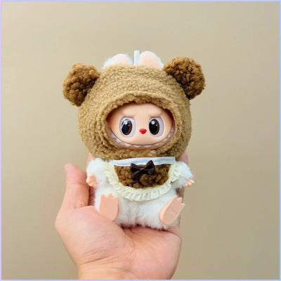 Toy figure in a bear costume held in a hand against a beige background