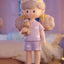 Toy figure of a girl in pajamas holding a teddy bear in a bedroom setting
