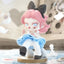 Anime-style figurine with pink hair and a black bow, sitting on a surface.