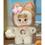 Stuffed animal toy with a face, wearing a brown and white outfit with pink bows, in a room setting.