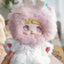 Toy figure with pink fluffy hood and white outfit held by a hand