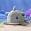 Plush shark toy on a sandy surface with an underwater background