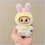 Plush toy with bunny ears held in a hand against a beige background