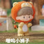 Toy figure of a lion with a child-like face, wearing an orange hood, on a blurred outdoor background.