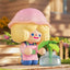 Toy figure with a pink mushroom hat holding a small plant in a garden setting