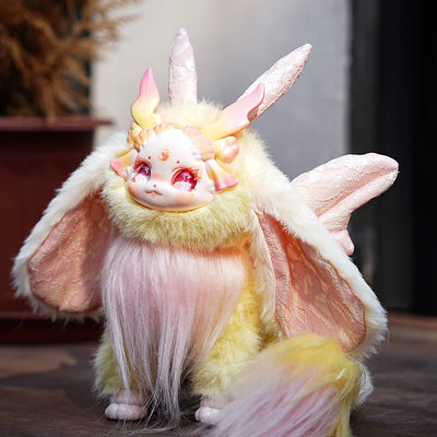 Plush toy with unicorn and bat design on a wooden surface