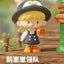 Toy figure of a penguin-like character with a hat and backpack, standing next to a signpost with text.