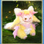 Plush toy of a fantasy creature with pink and yellow colors sitting on grass.