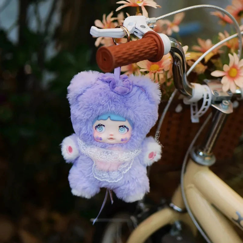 Plush keychain with cartoon character hanging from a bicycle handlebar