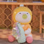 Toy figure with a yellow hat and pink shoes holding a colorful object on a wooden surface.