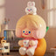 Children's toy figure with a bunny on head and a cup in hand, set against a blurred indoor background.